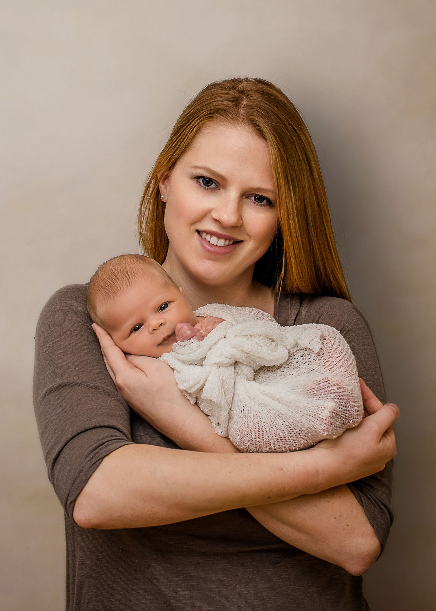 red-haired mom holding baby girl wrapped in her arms