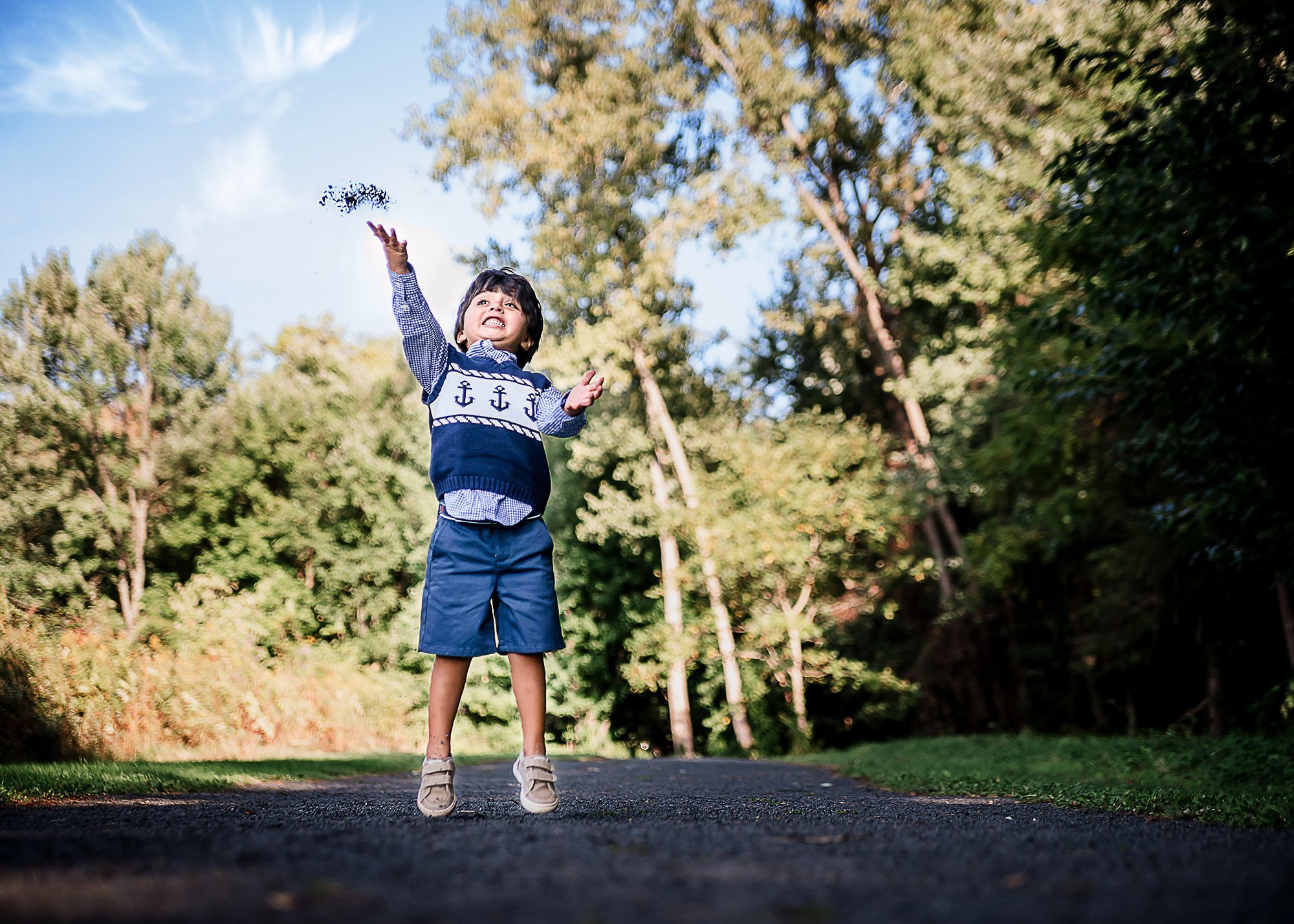 little boy excitedly throwing small rocks into the air outside
