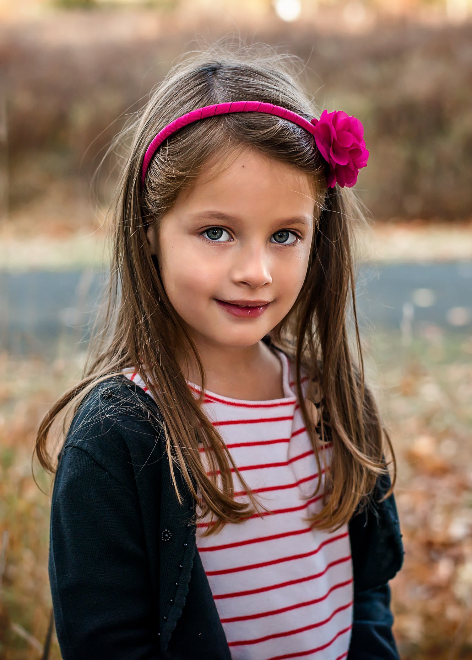 headshot of young girl wearing a bright pink headband in fall