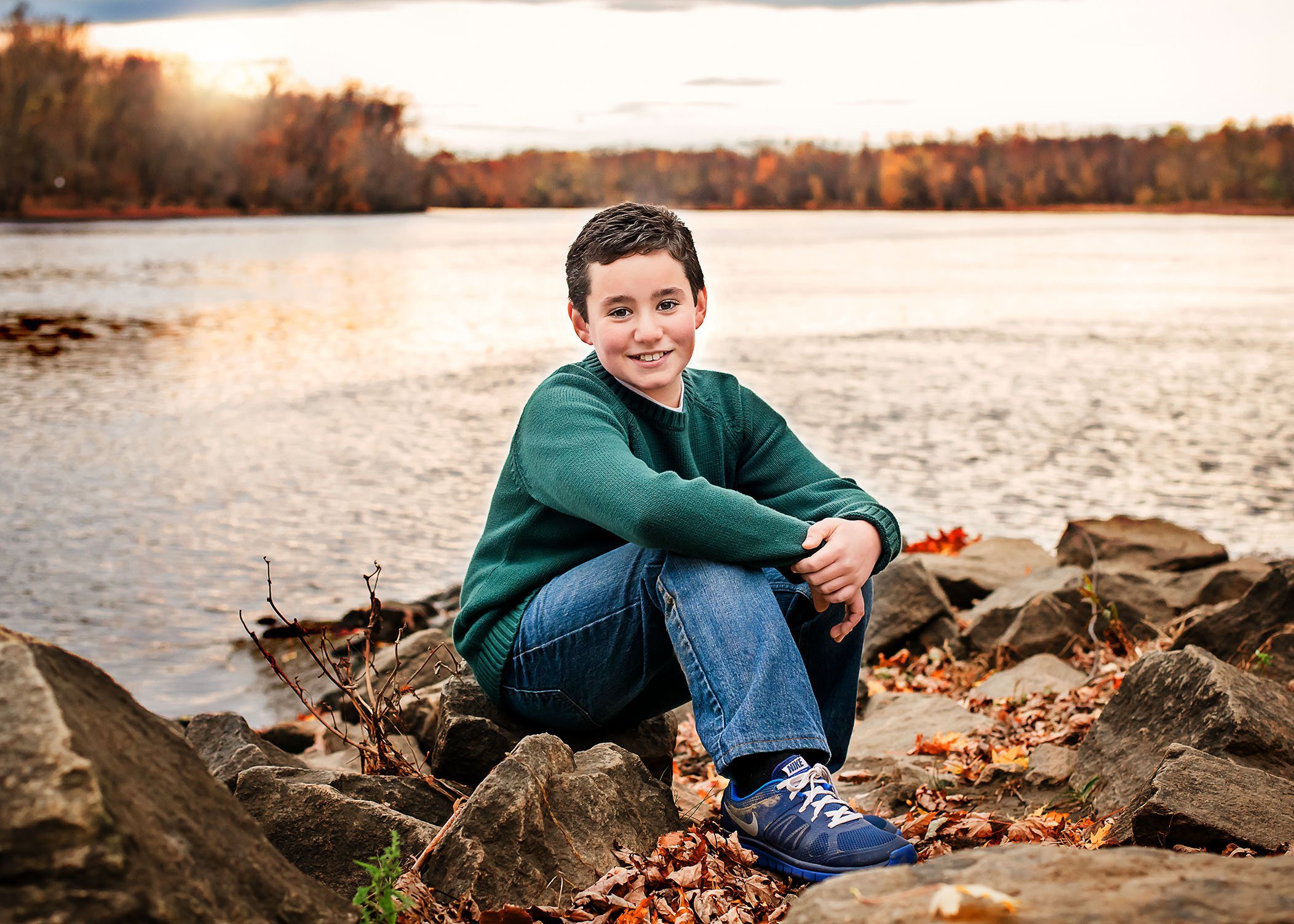 little boy sitting on rocks at the Connecticut river in Fall