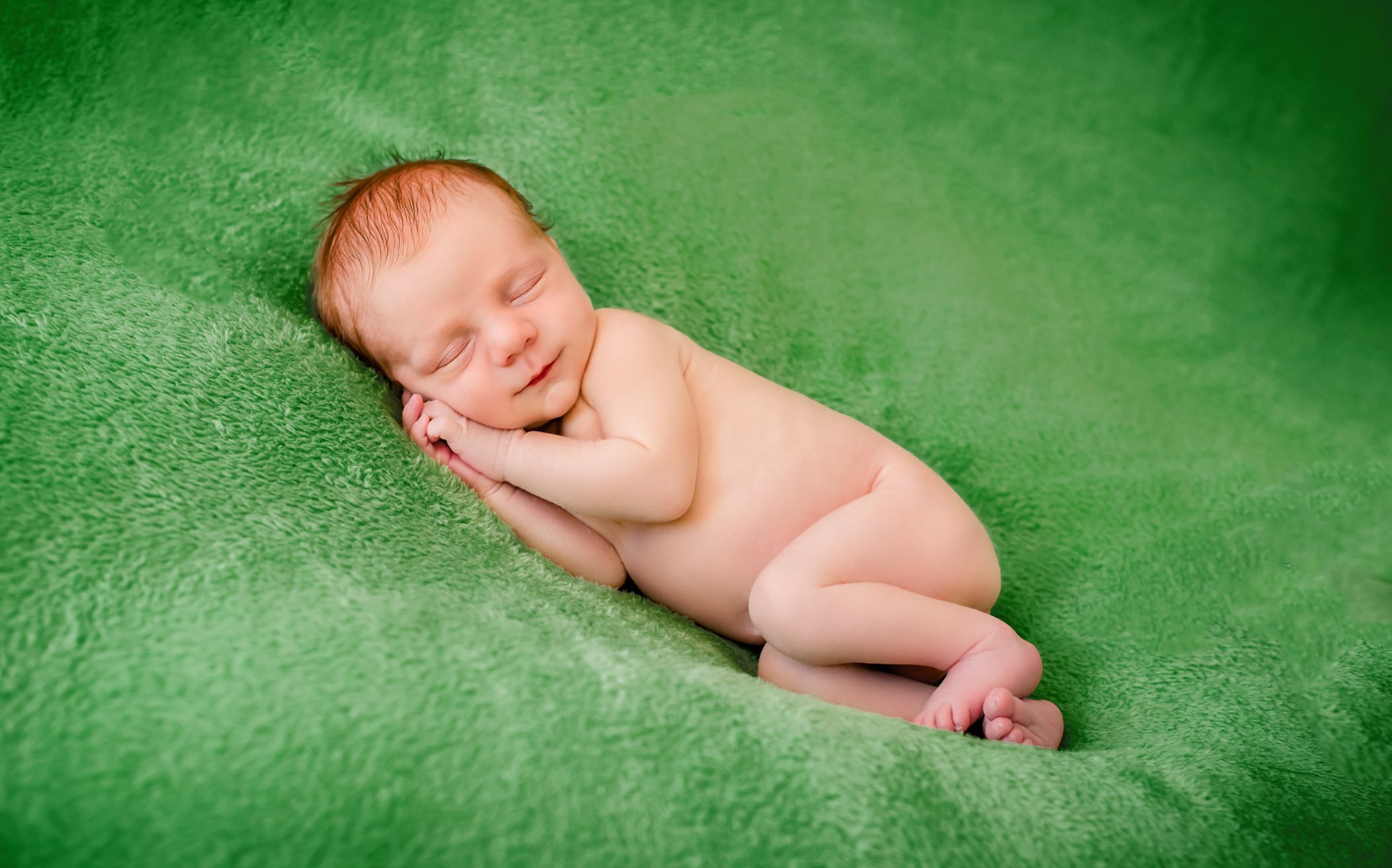 Newborn baby red hair sleeping on green blanket