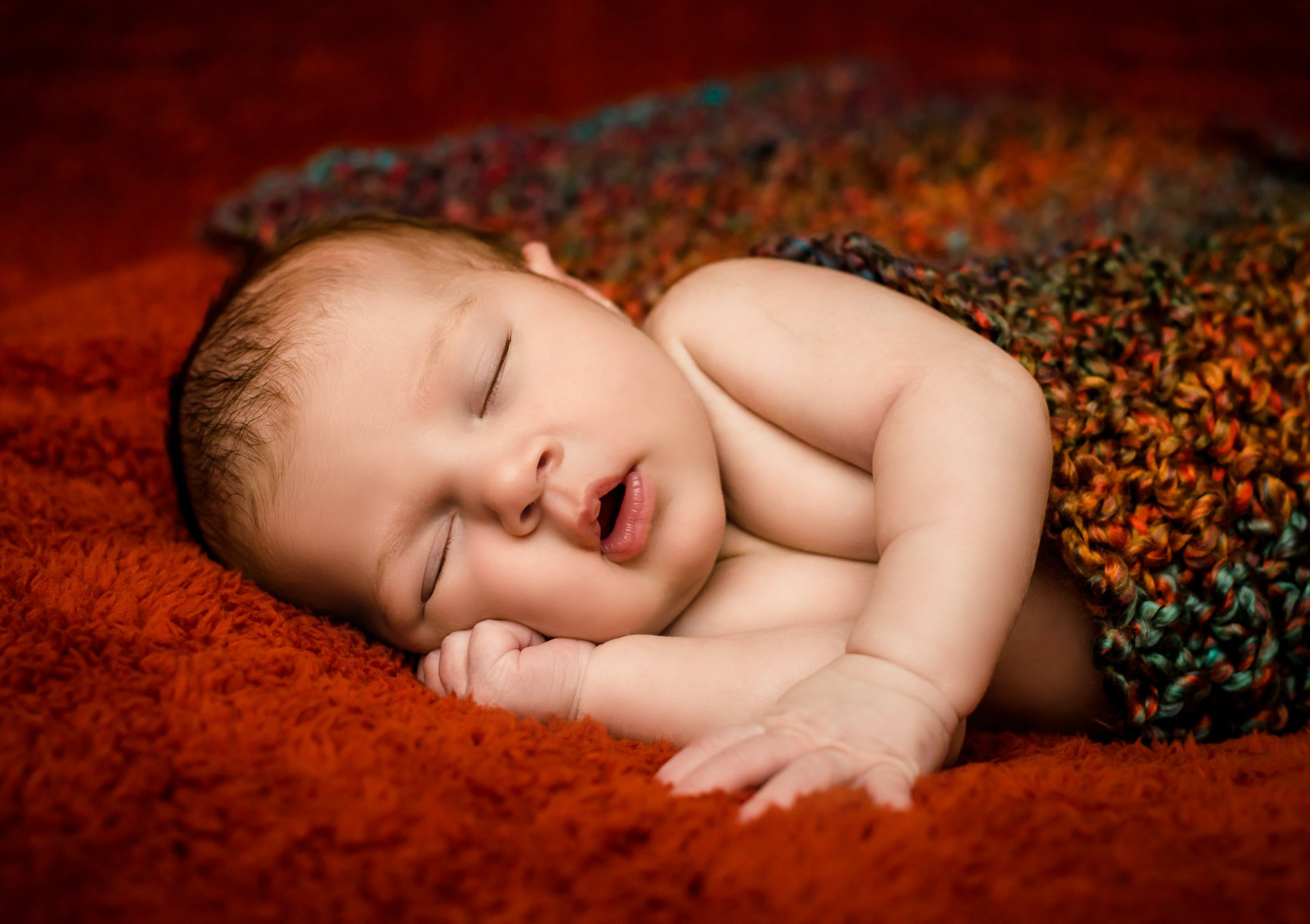 newborn sleeping on her side with her mouth open looking peaceful