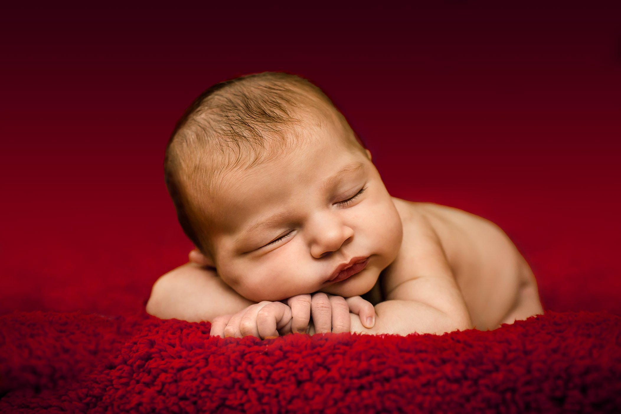 newborn Christmas photos sleeping on deep red blanket