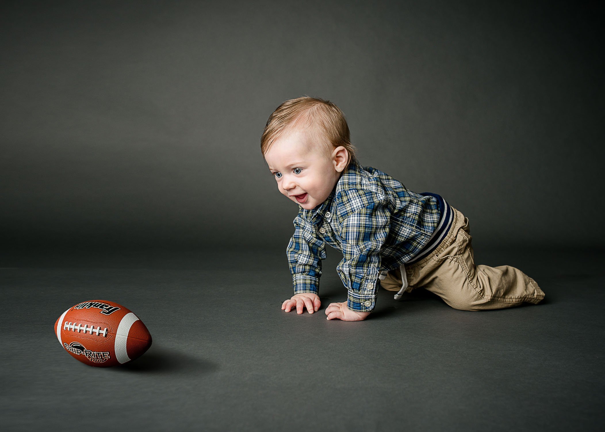 6 month old baby boy crawling towards a football