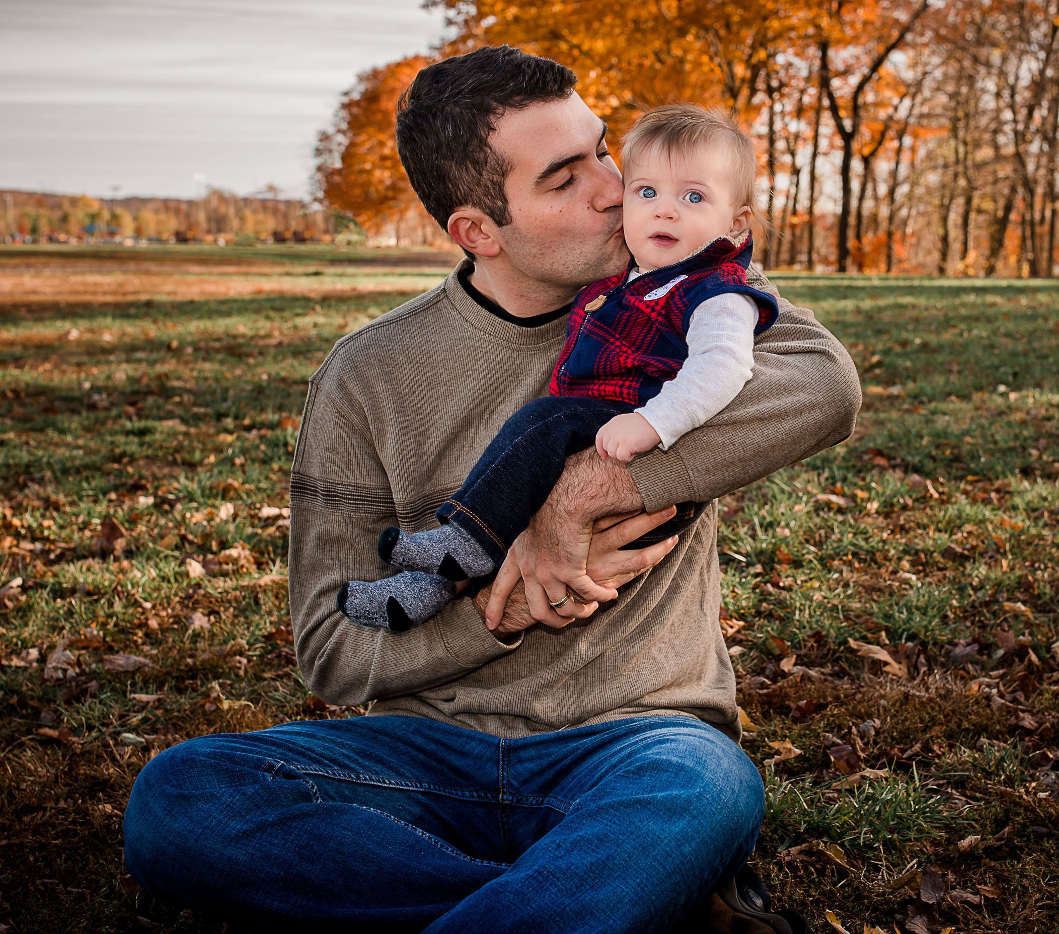 Dad kissing baby boy on cheek outside in fall