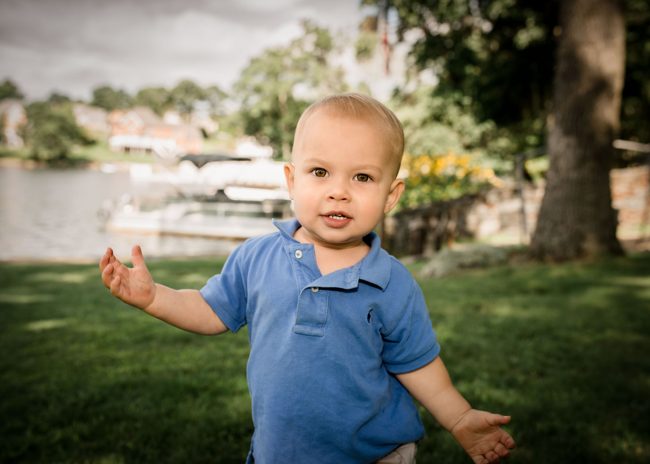 one year old boy toddling along outside in the garden by the lake