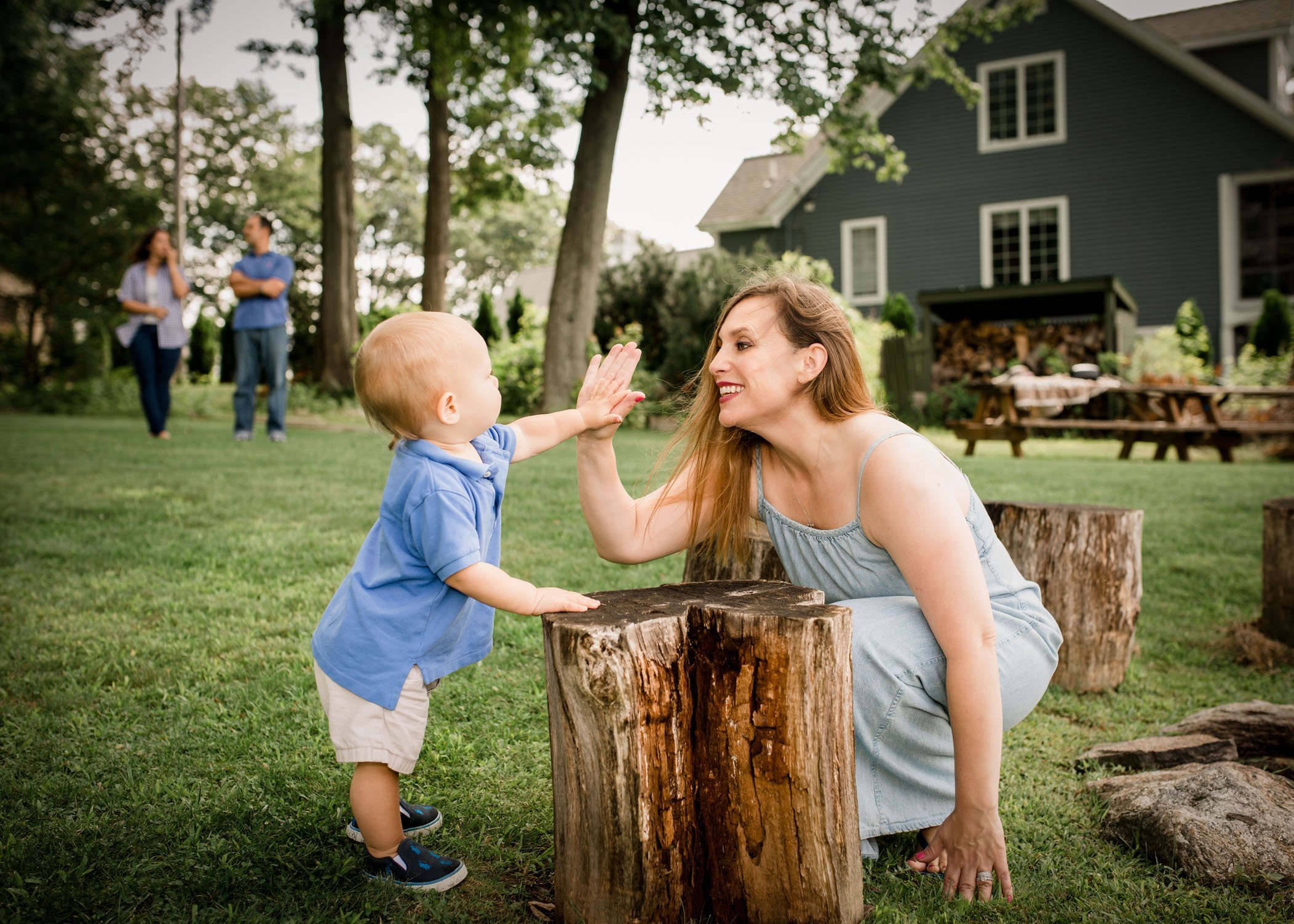 one year old boy giving Mom a high 5 outside in the garden