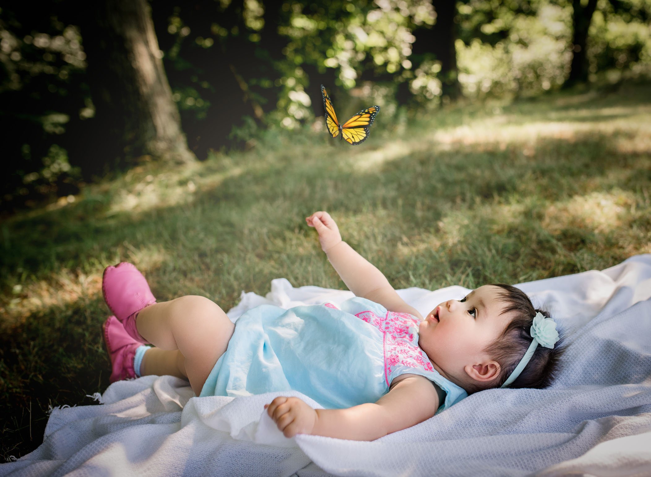 6 month old baby girl lying on a blanket looking up at a butterfly