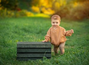 toddler girl standing in nature with hand on wooden crate