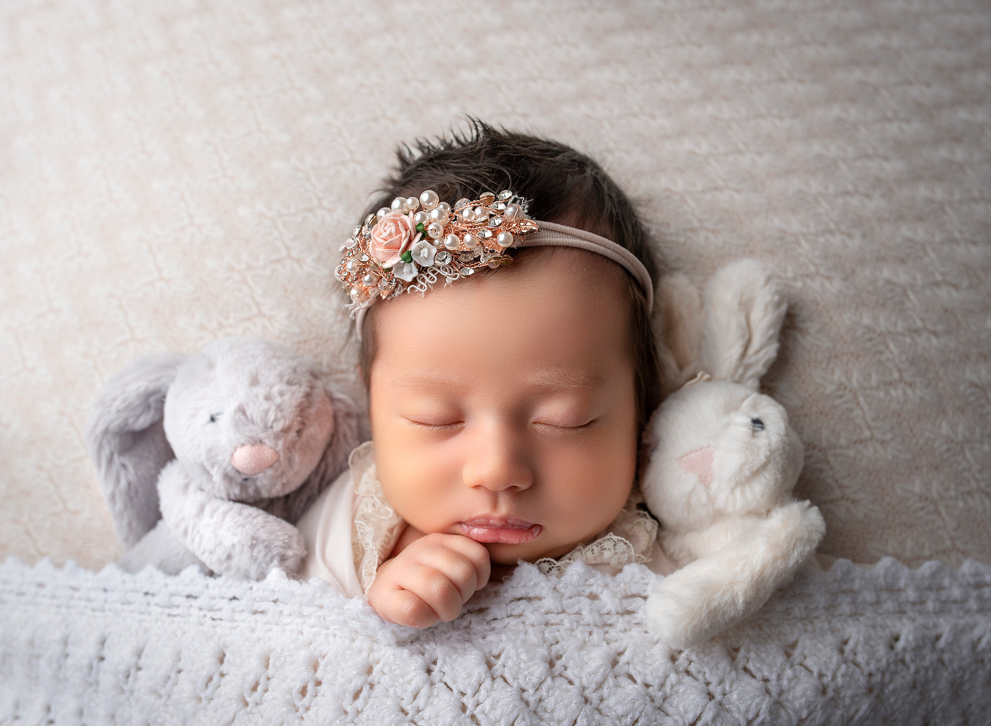 posed newborn photography session Sophie peacefully sleeping with two cuddly bunnies. 