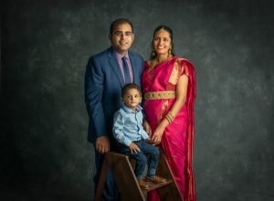 pregnant woman posing with husband and son wearing traditional costume