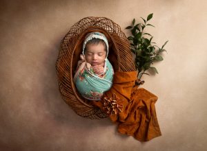 newborn baby girl asleep inside bohemian basket
