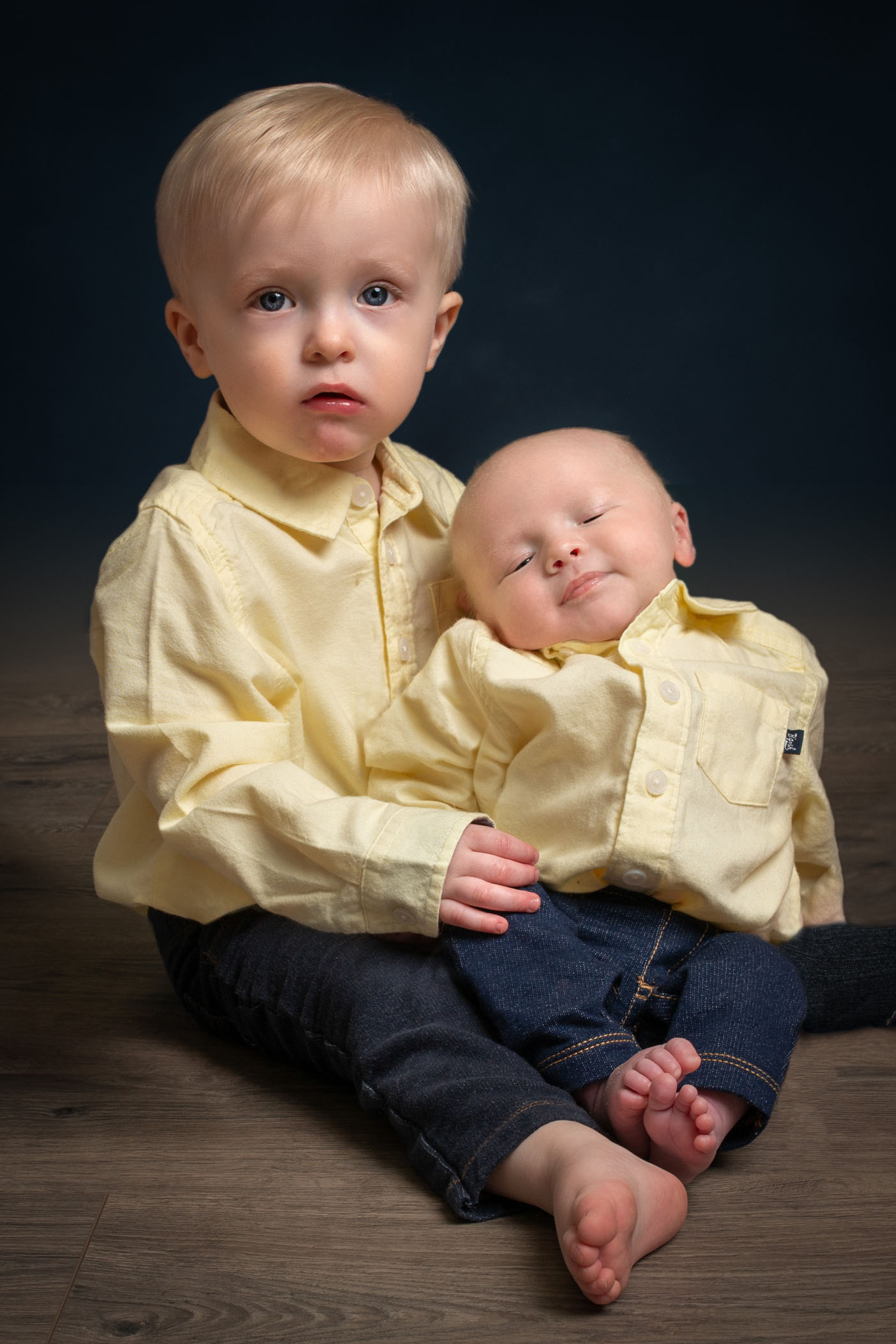 2 year old brother holding newborn brother and looking at camera