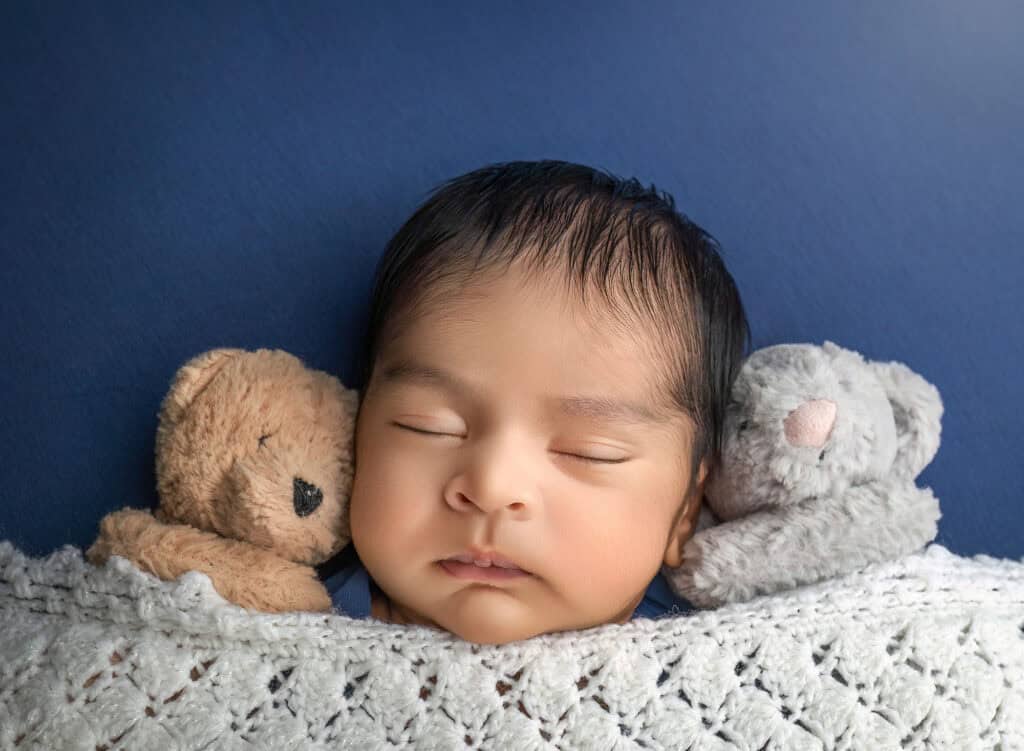 newborn and family photography close-up of baby between two plush bears on navy blanket