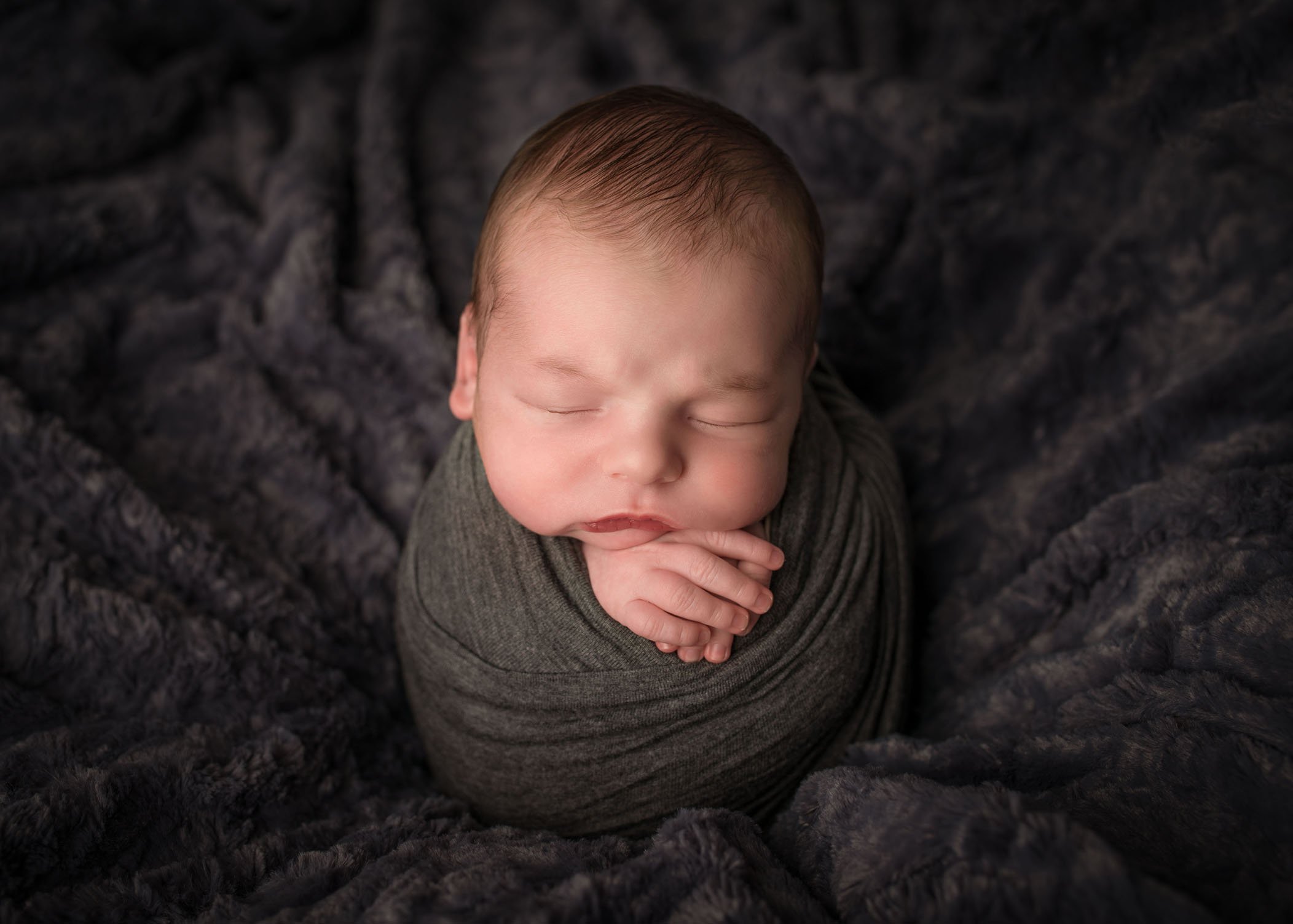 newborn boy swaddled and sleeping in potato sack pose