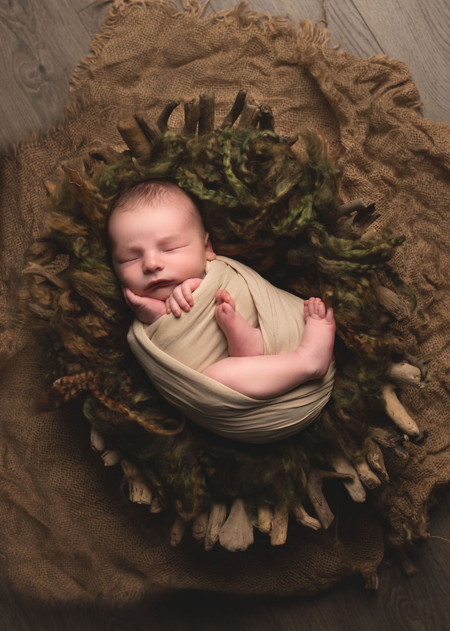 newborn boy swaddled in rustic wooden bowl