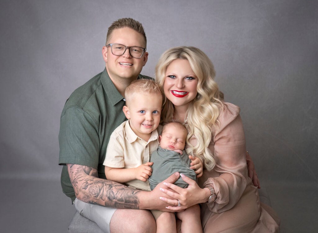 newborn photos what to wear family of 4 smiling at camera