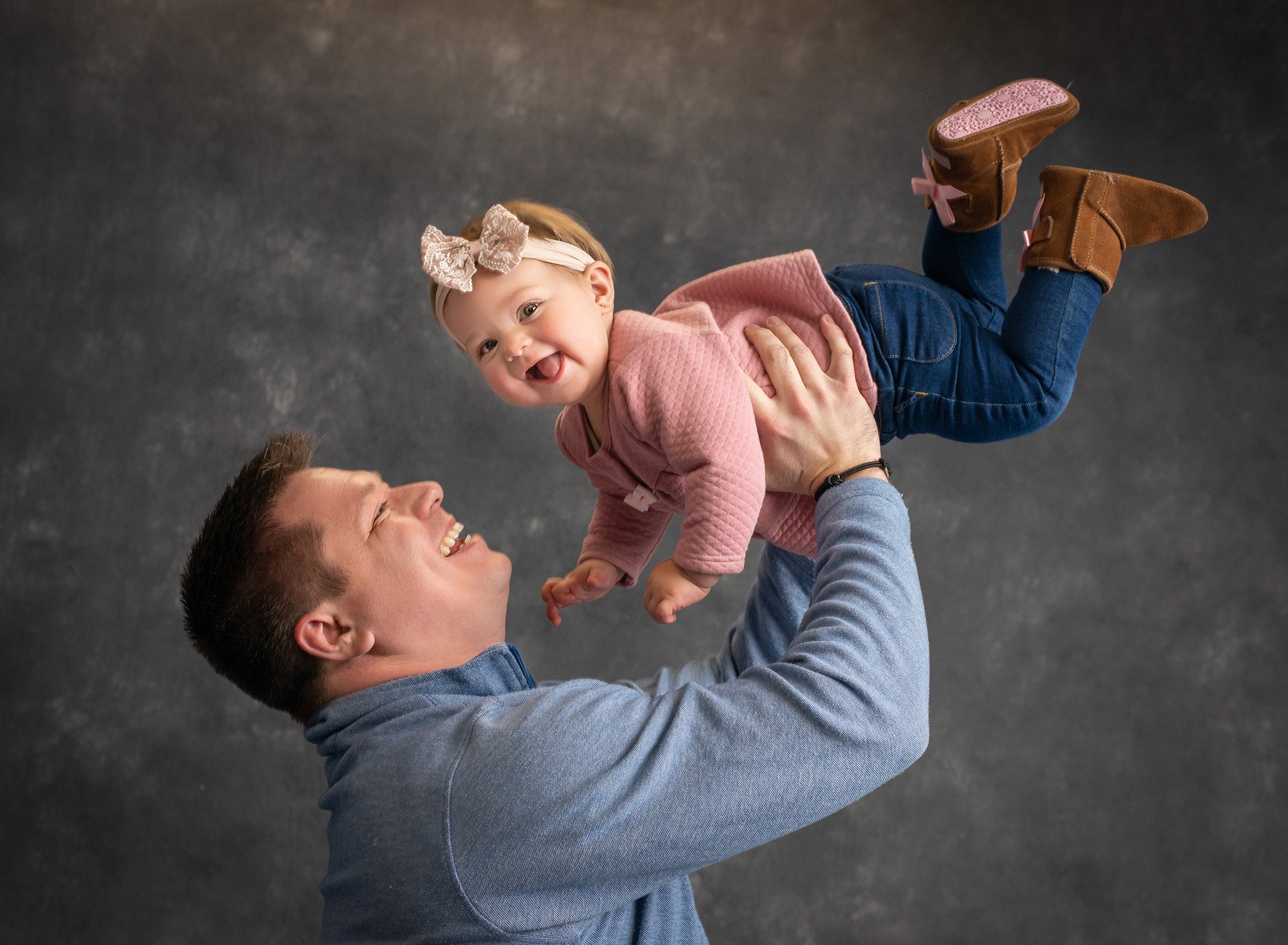 little girl in pink laughing as dad holds her in the air