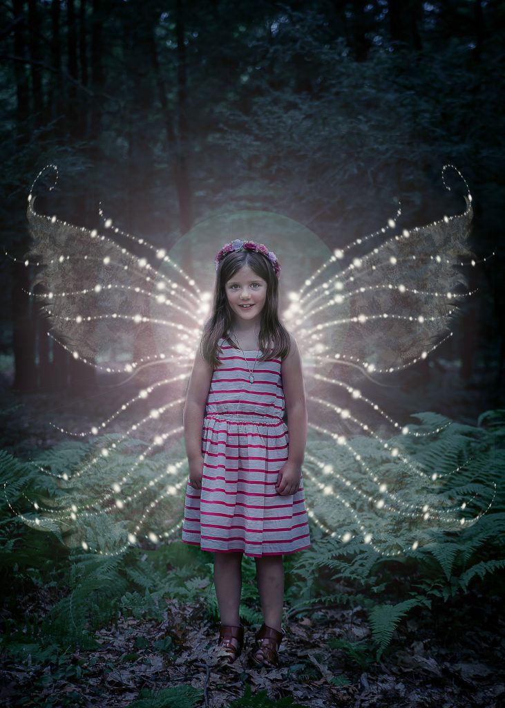 little girl with glowing fairy wings outside at nighttime