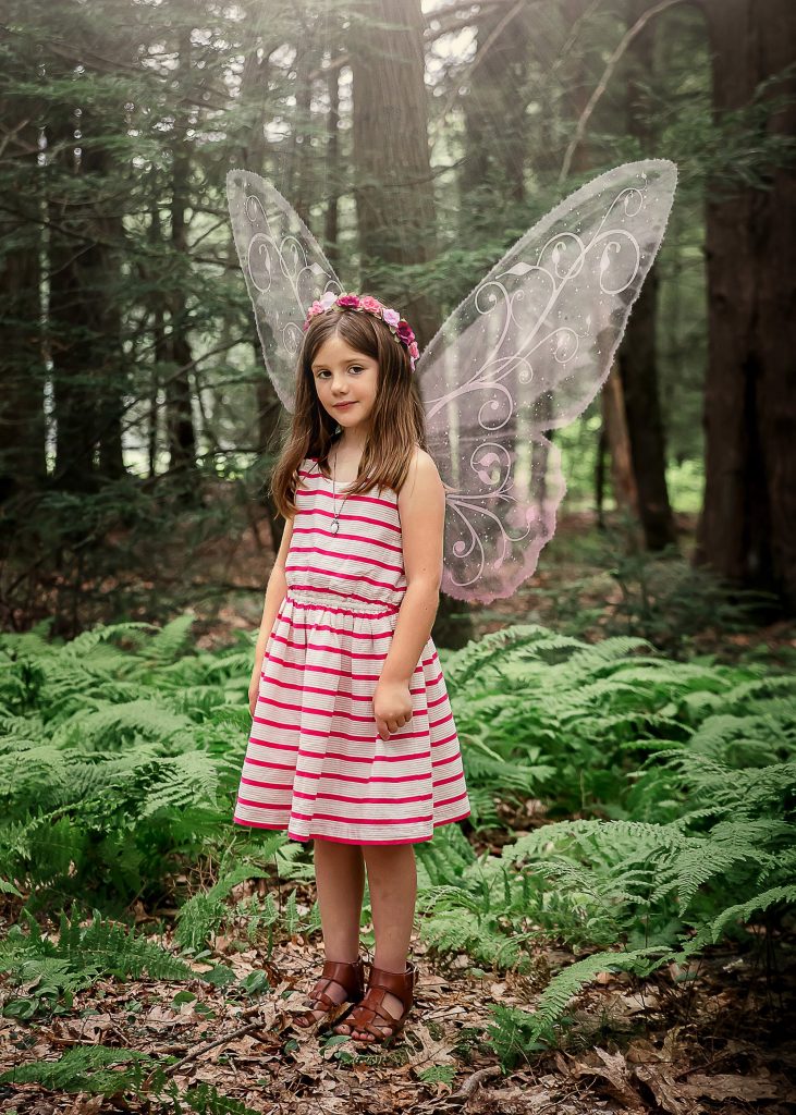 little girl in the woods with pink fairy wings