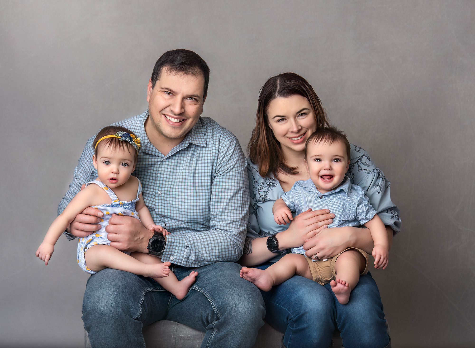 Family portrait of parents holding twins all wearing blue