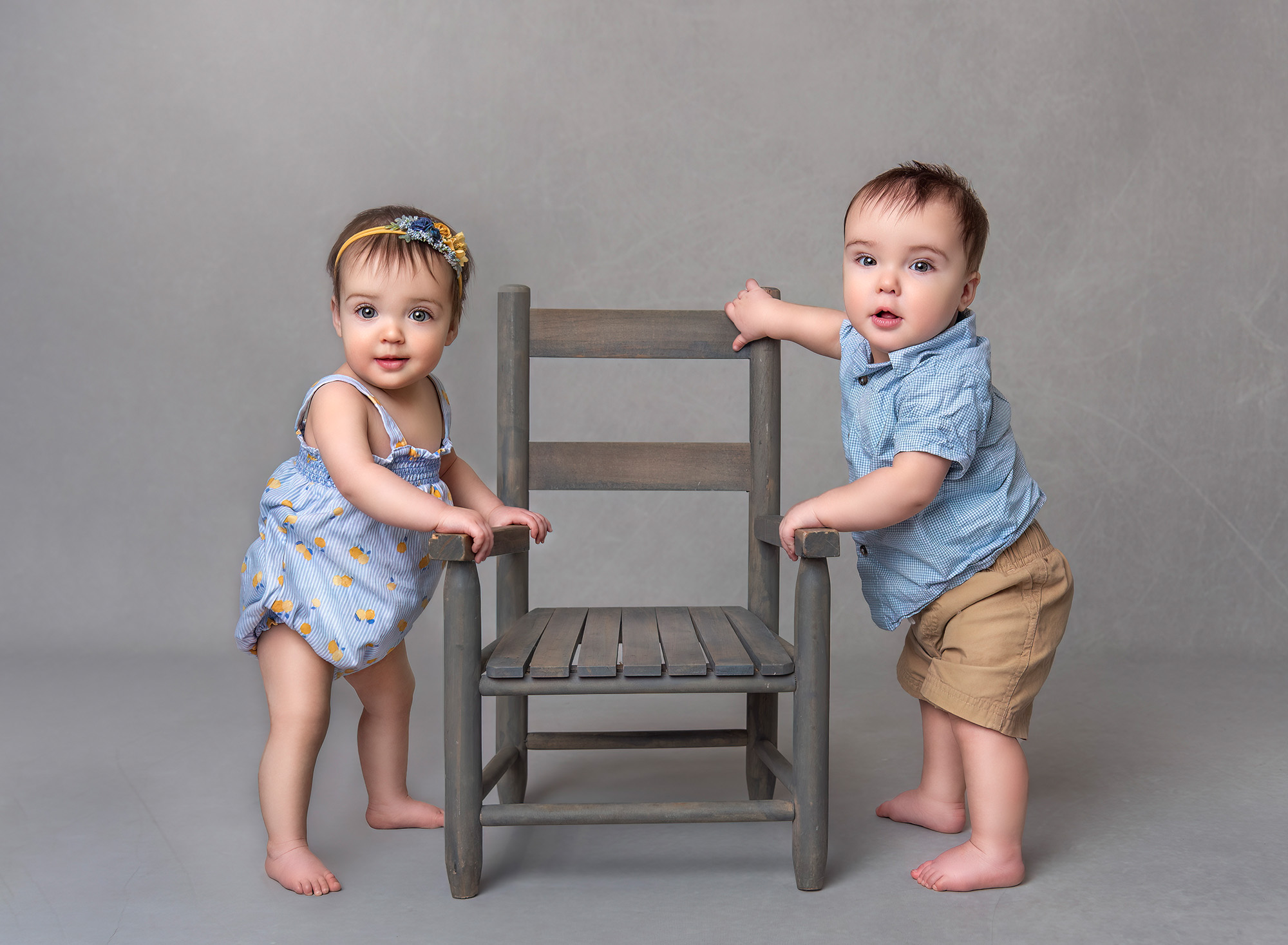 Twin Photo Shoot Star Wars Cake Smash Twin boy and girl standing up opposite each other holding on to a chair