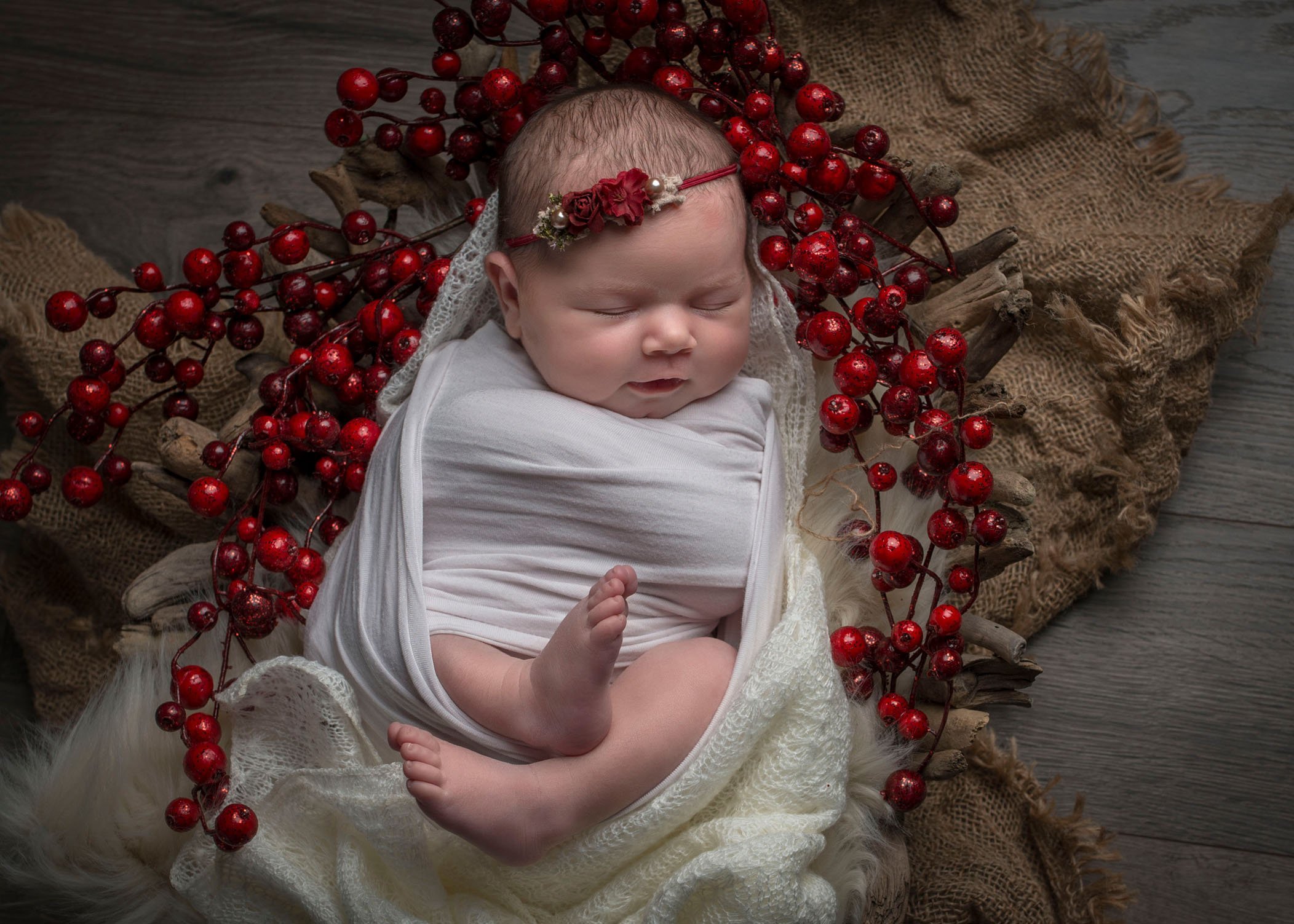 newborn baby girl asleep in cranberry wreath