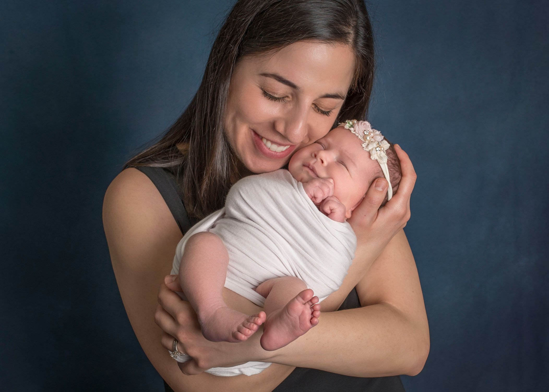 Mom cuddling newborn close to her face and smiling