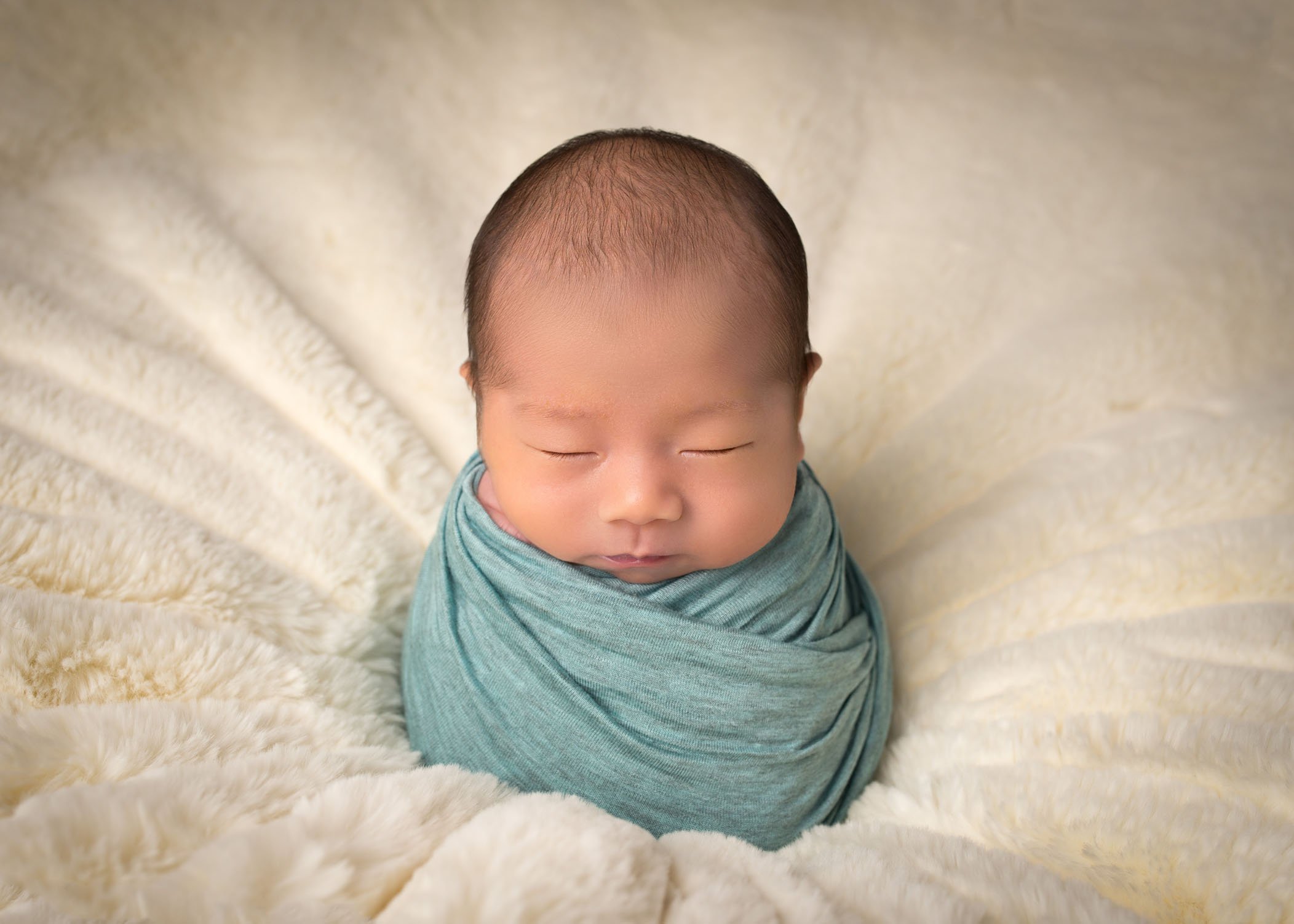 swaddled Chinese newborn baby sleeping in potato sack pose