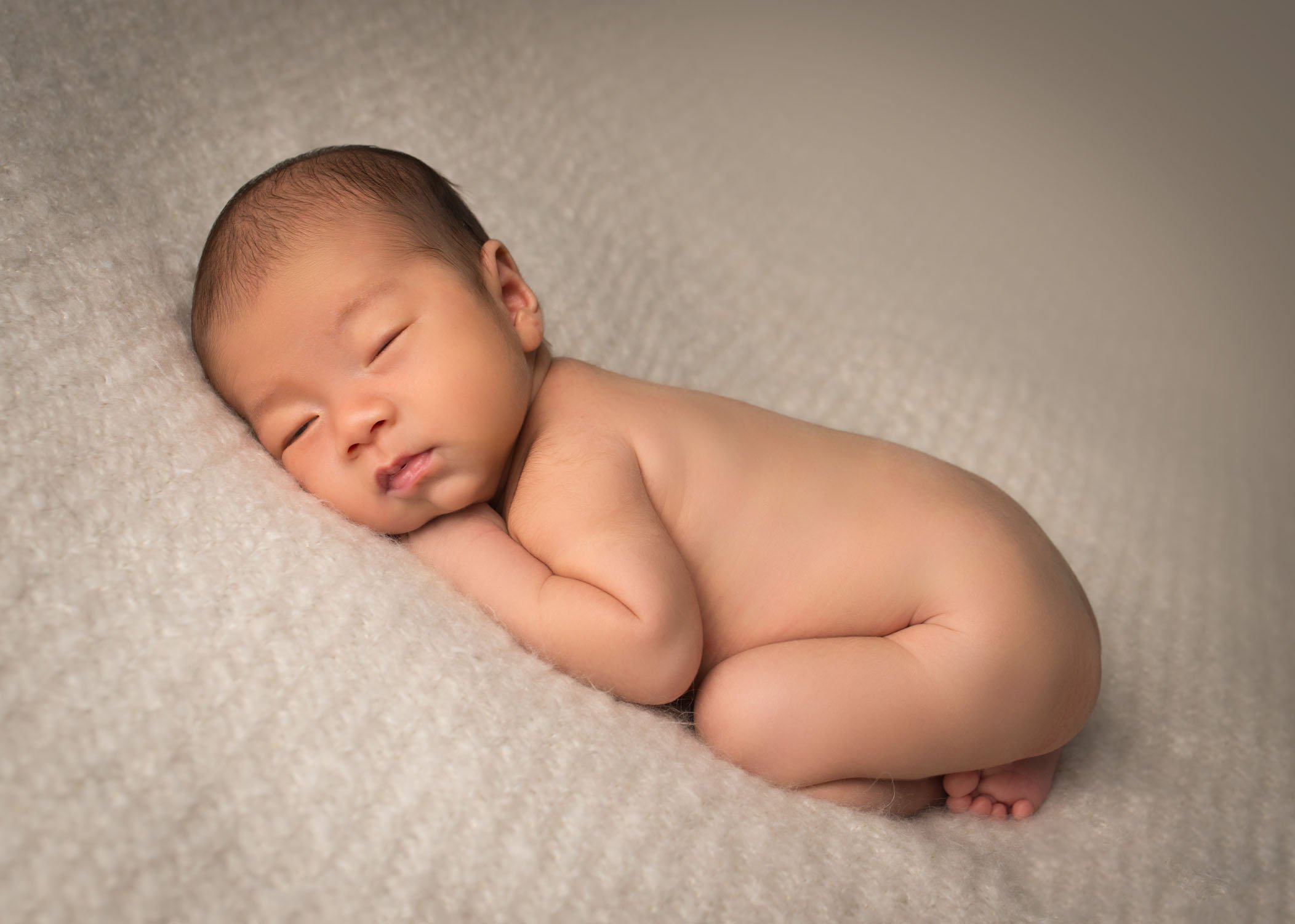 adorable newborn photo Chinese newborn baby boy sleeping on tummy on cream blanket