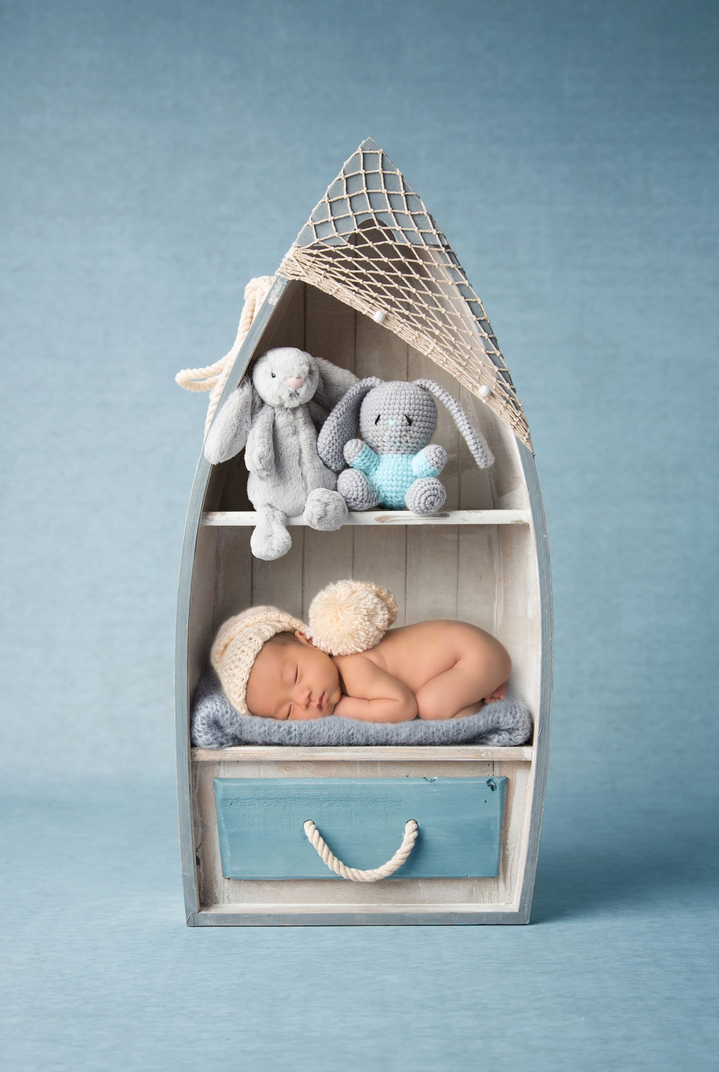 adorable newborn photo newborn baby sleeping in boat cabinet with stuffed animals