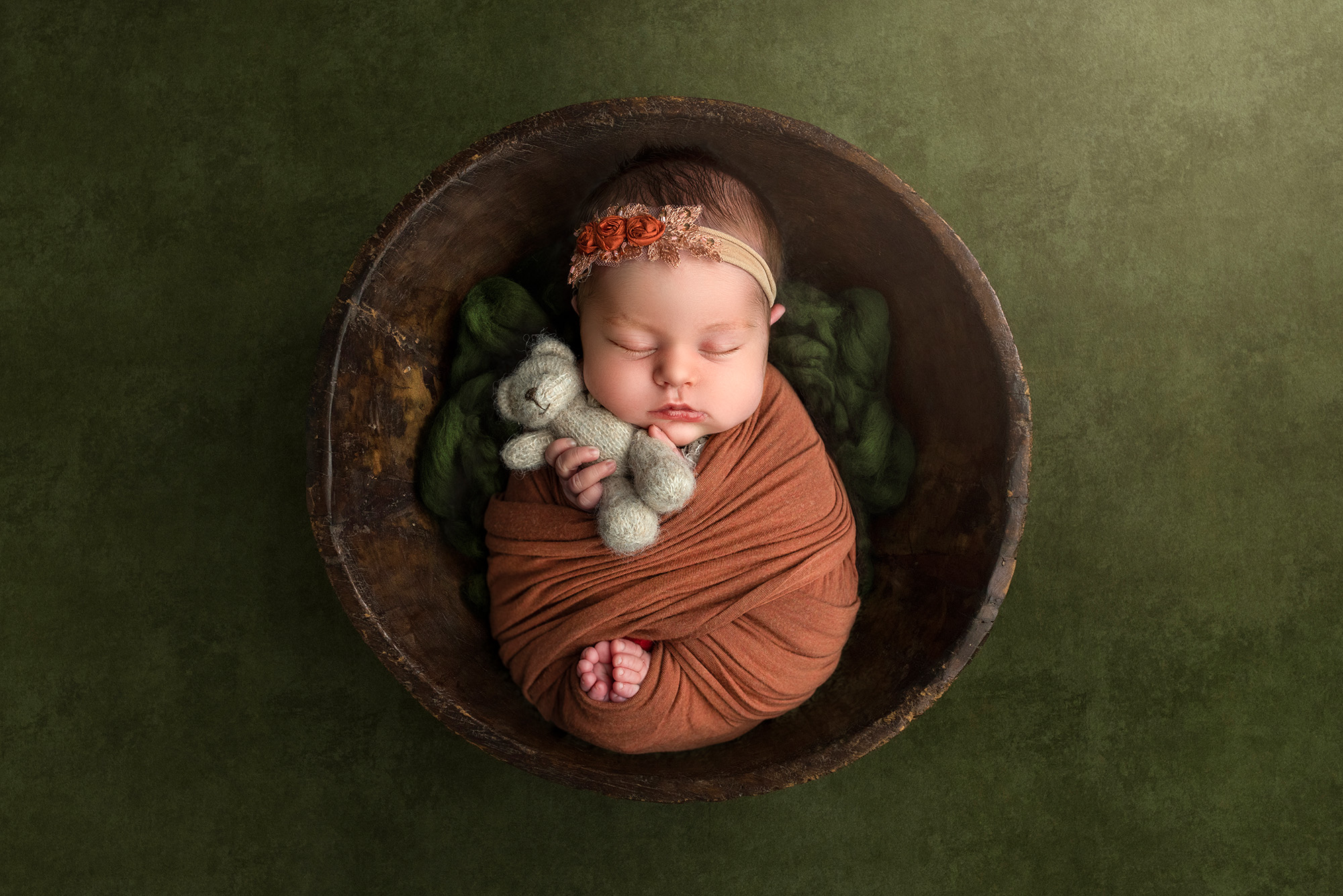 best newborn photography baby sleeping in a bowl holding a teddy bear