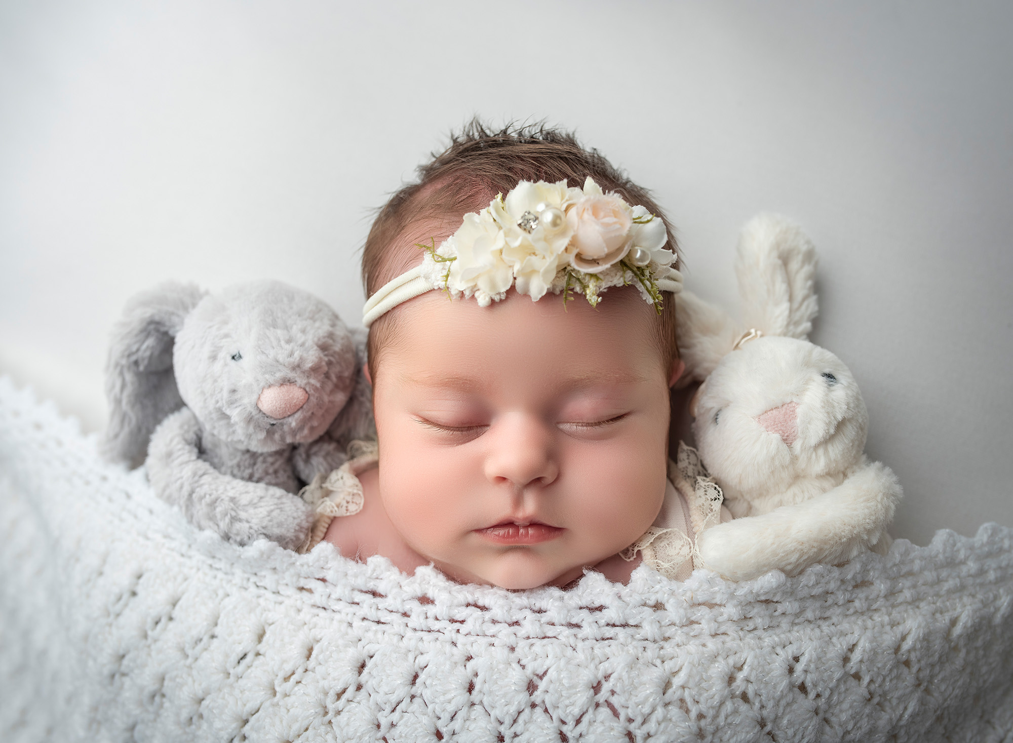 best newborn photography sleeping baby tucked in with her bunny friends to nap