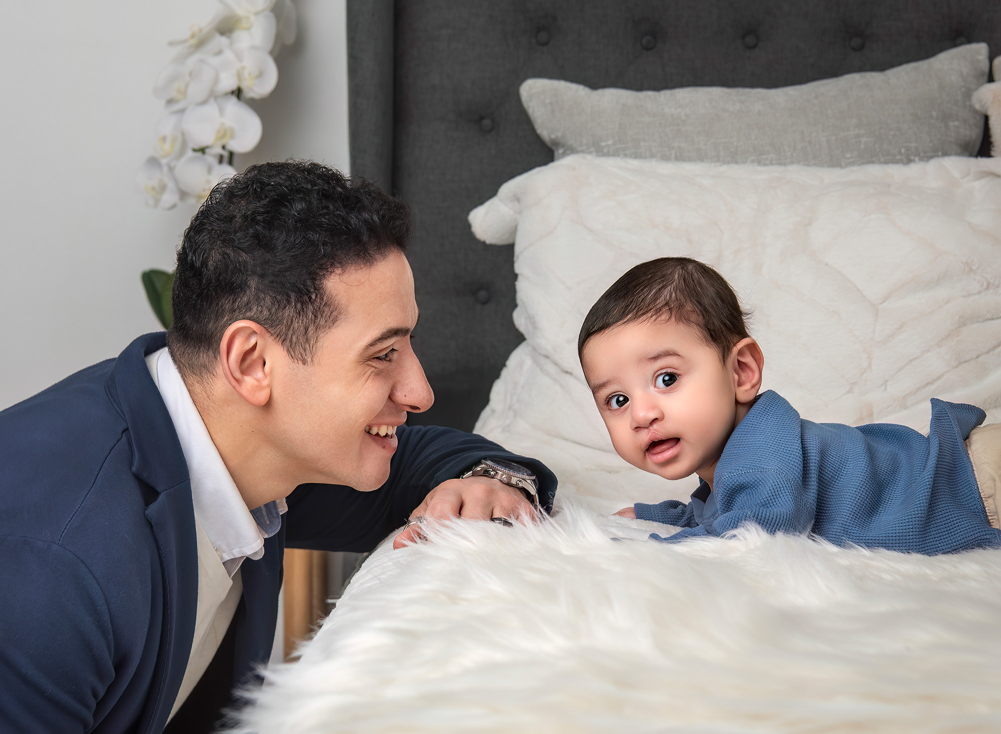 Father looking at three month old laying on the bed