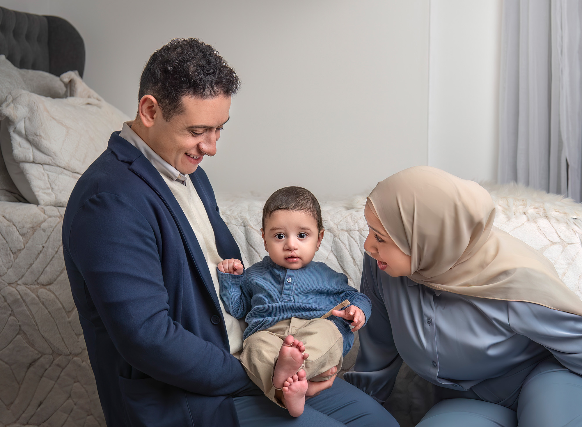 Family of three with baby in the center, parents looking at him lovingly