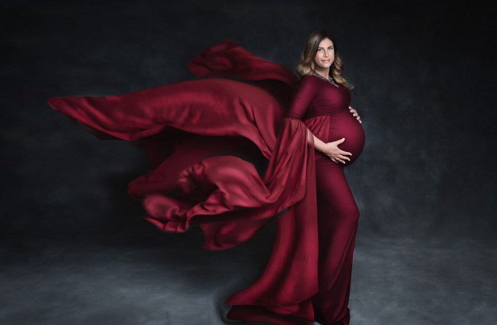 pregnant woman wearing cranberry maternity dress flowing in the wind