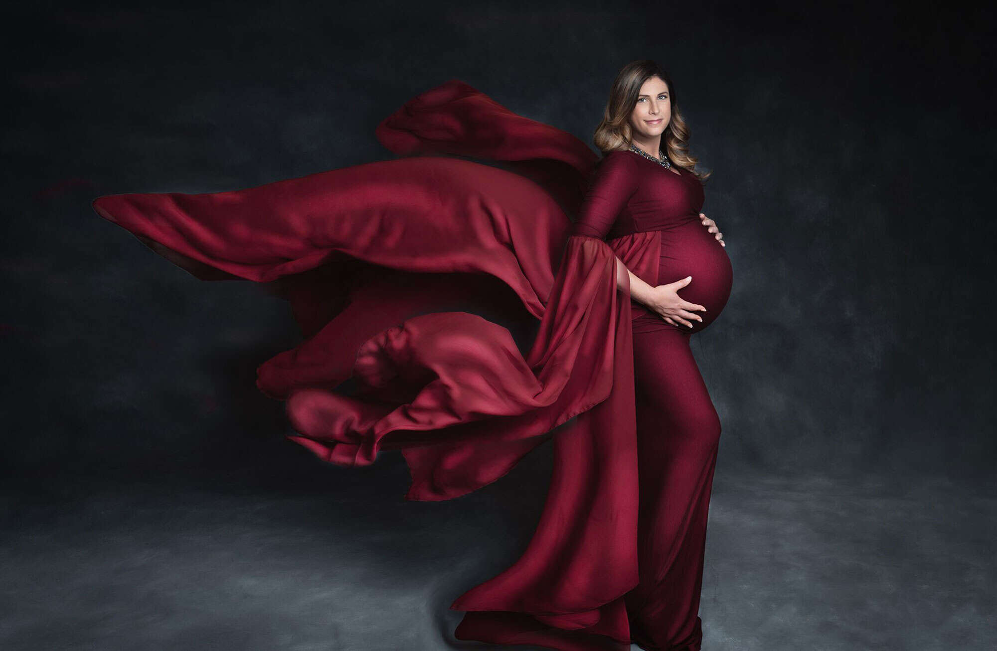 pregnant woman wearing cranberry maternity dress flowing in the wind