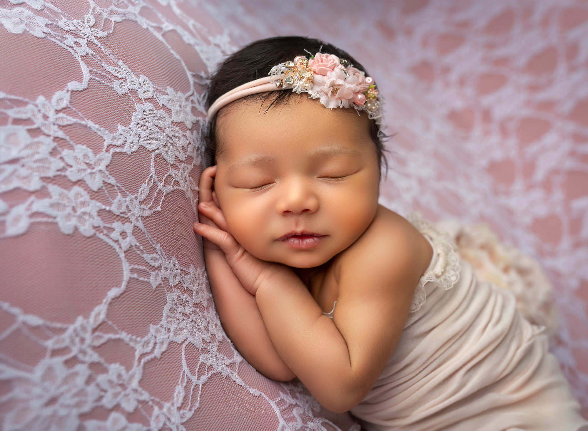 newborn baby girl asleep resting head on her hands on peach lace backdrop