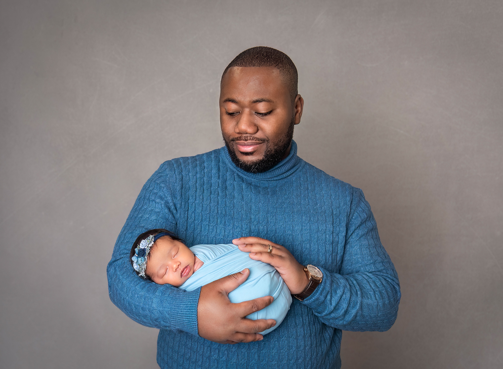 Newborn baby girl asleep in dad's arms