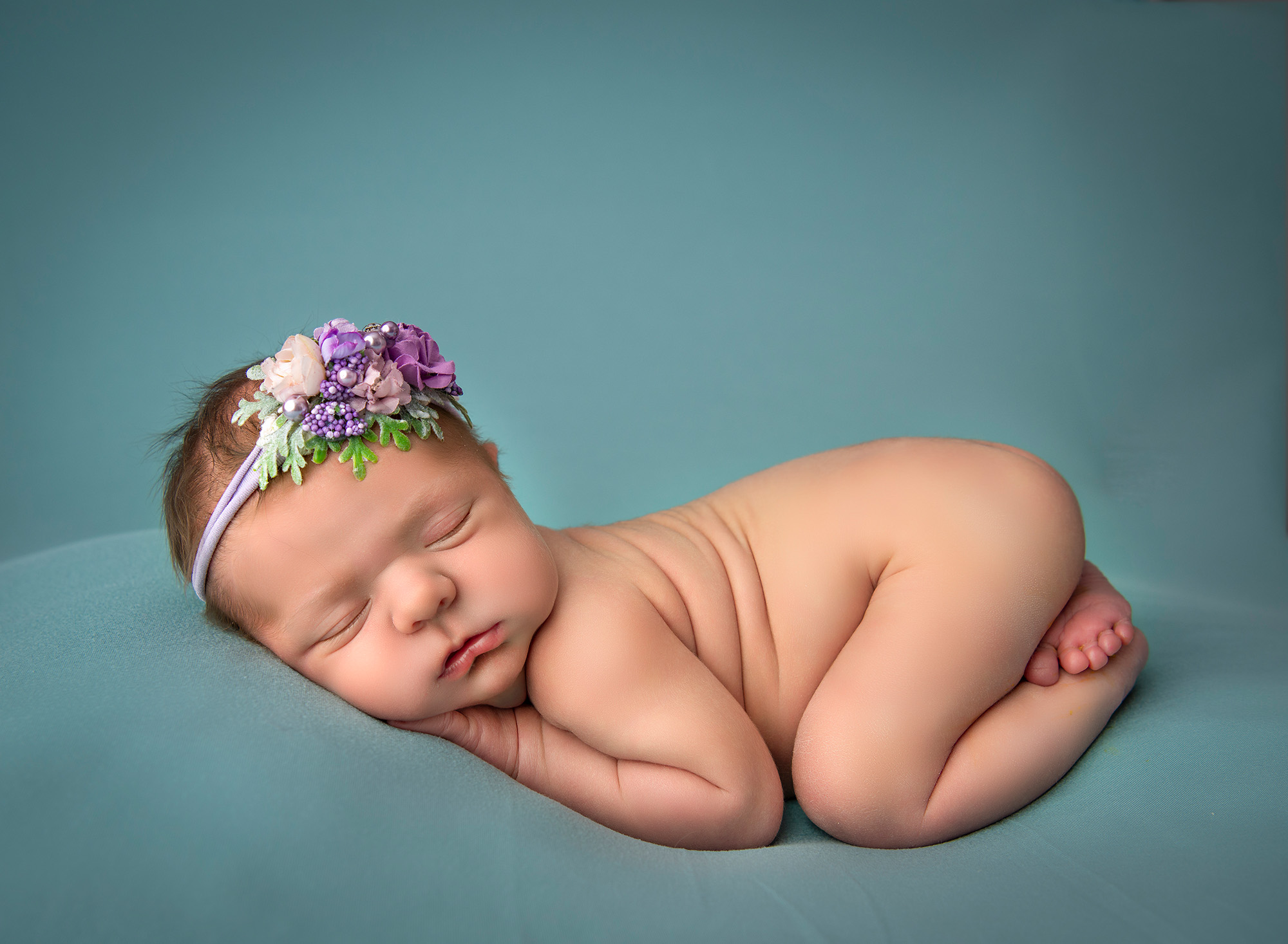 maternity and newborn photoshoot newborn baby in tushie up pose on a teal backdrop