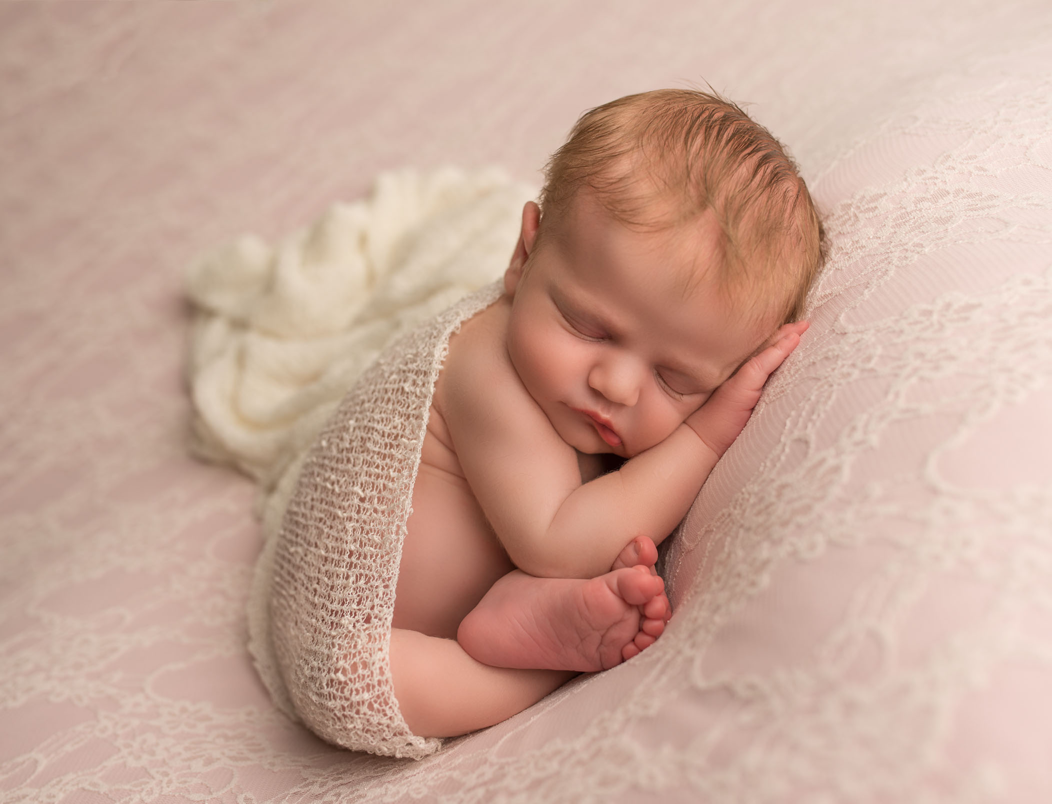 newborn in womb position with cream wrap on