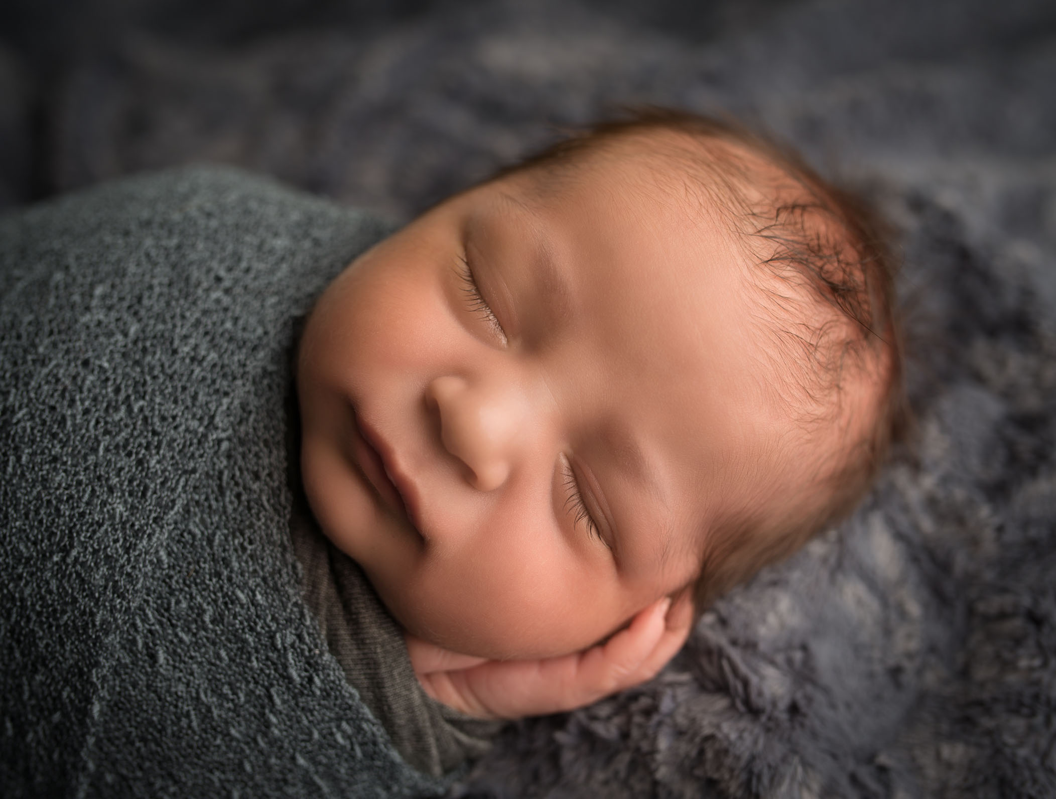 close up photo of newborn baby with long eyelashes and hands in prayer pose