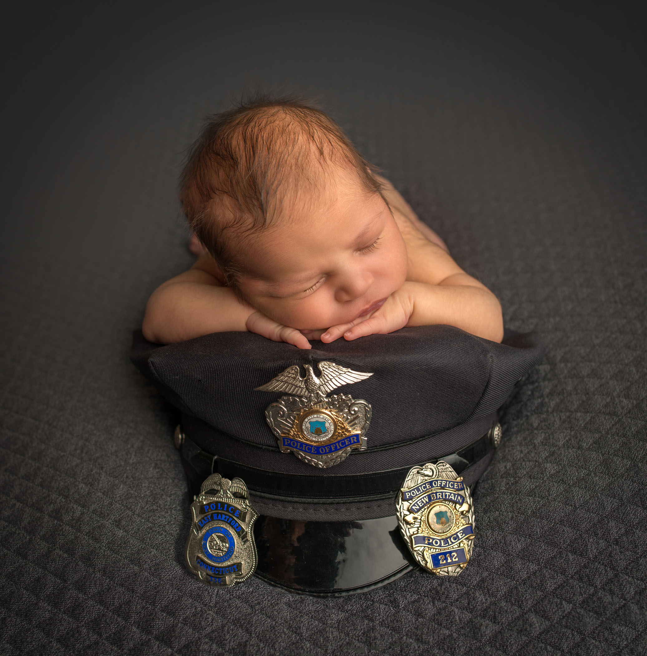newborn baby sleeping on police officer cover with parent's badges