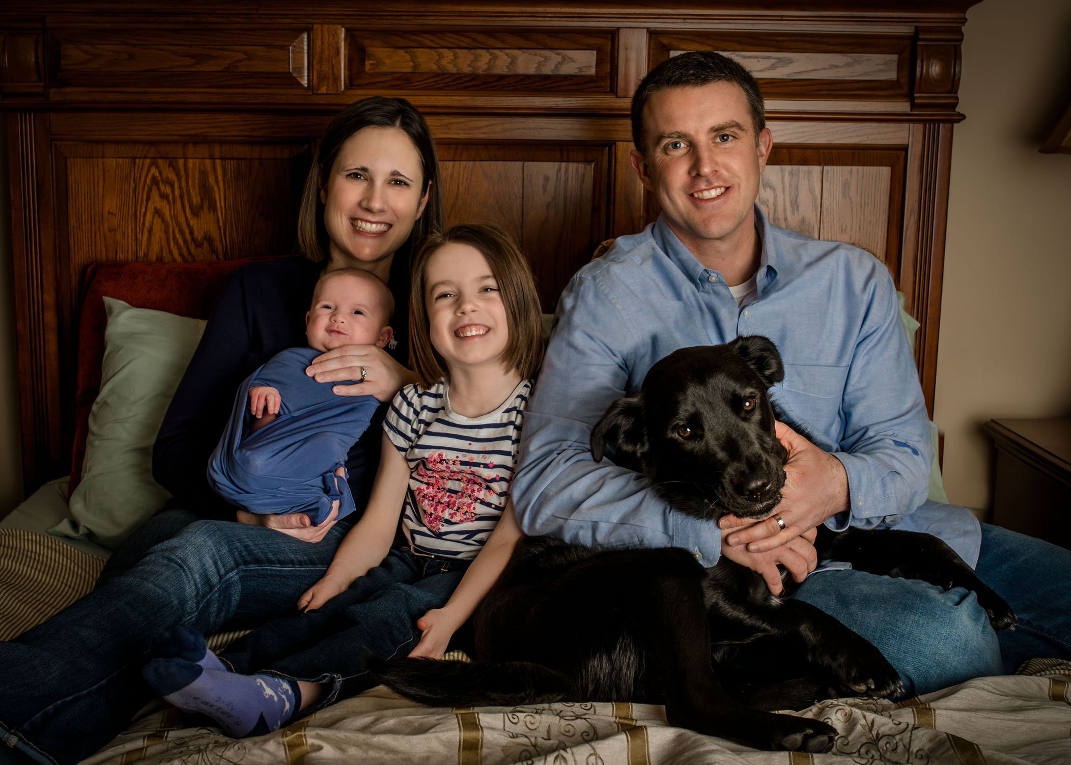 Family with 2 kids and dog on bed