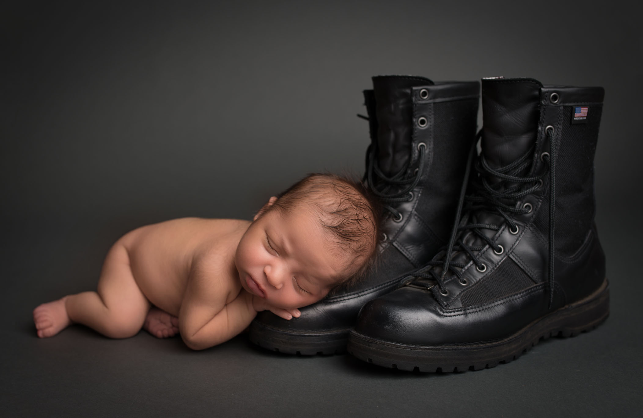 newborn baby sleeping on edge of Dad's police officer boots