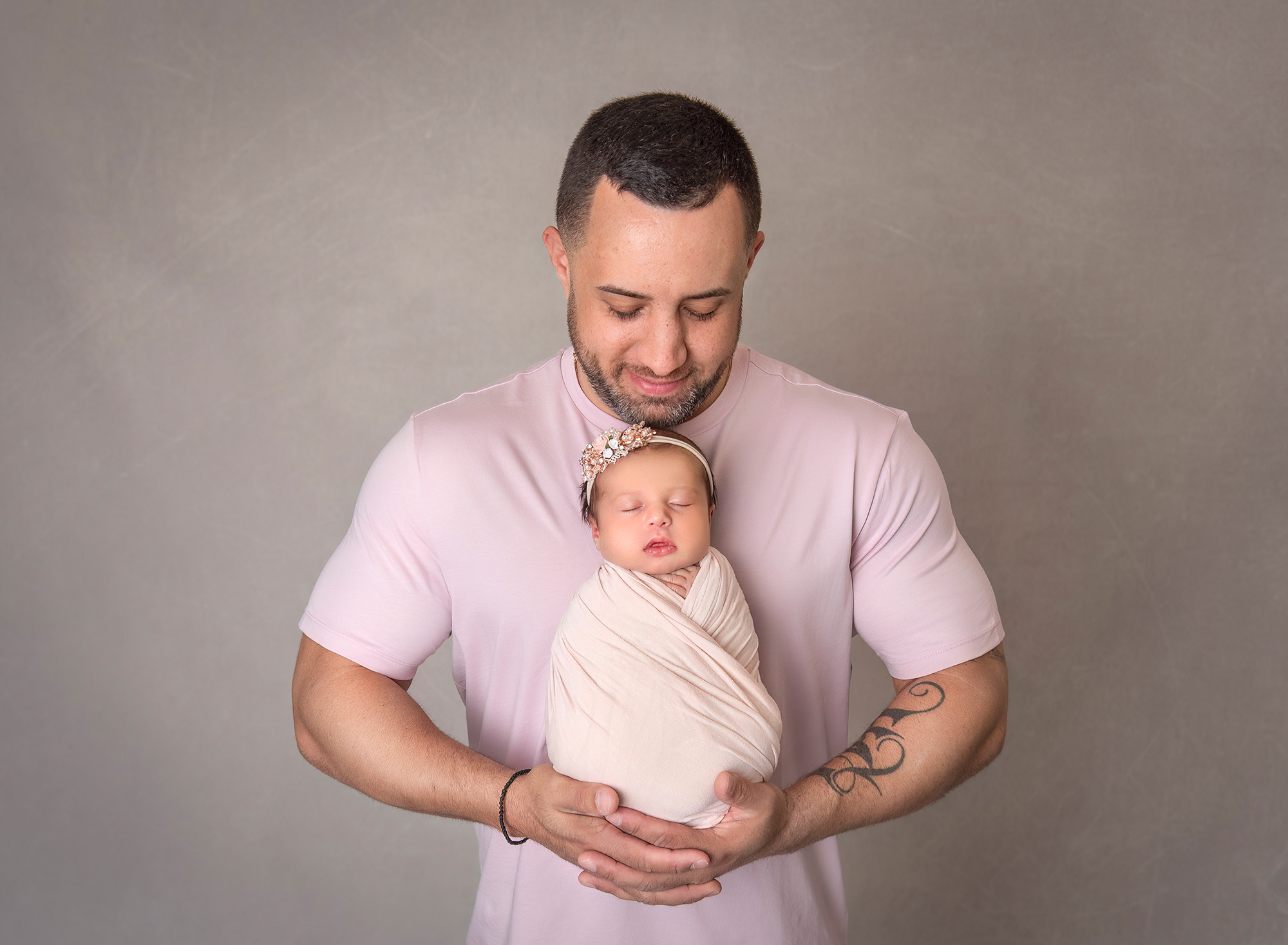 dad holding newborn daughter in front of his chest looking down at her