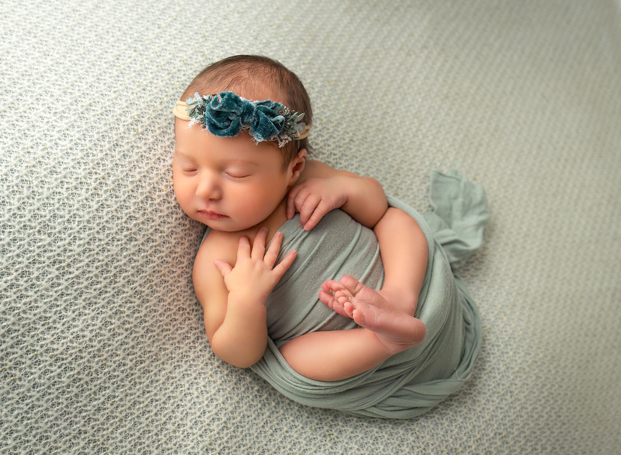 Newborn Maternity Photographer newborn baby girl asleep with her hands on her chest and feet together wearing a green headband