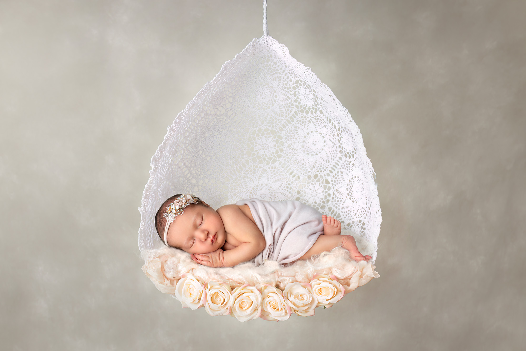 Newborn Maternity Photographer baby sleeping in a teardrop swing with roses