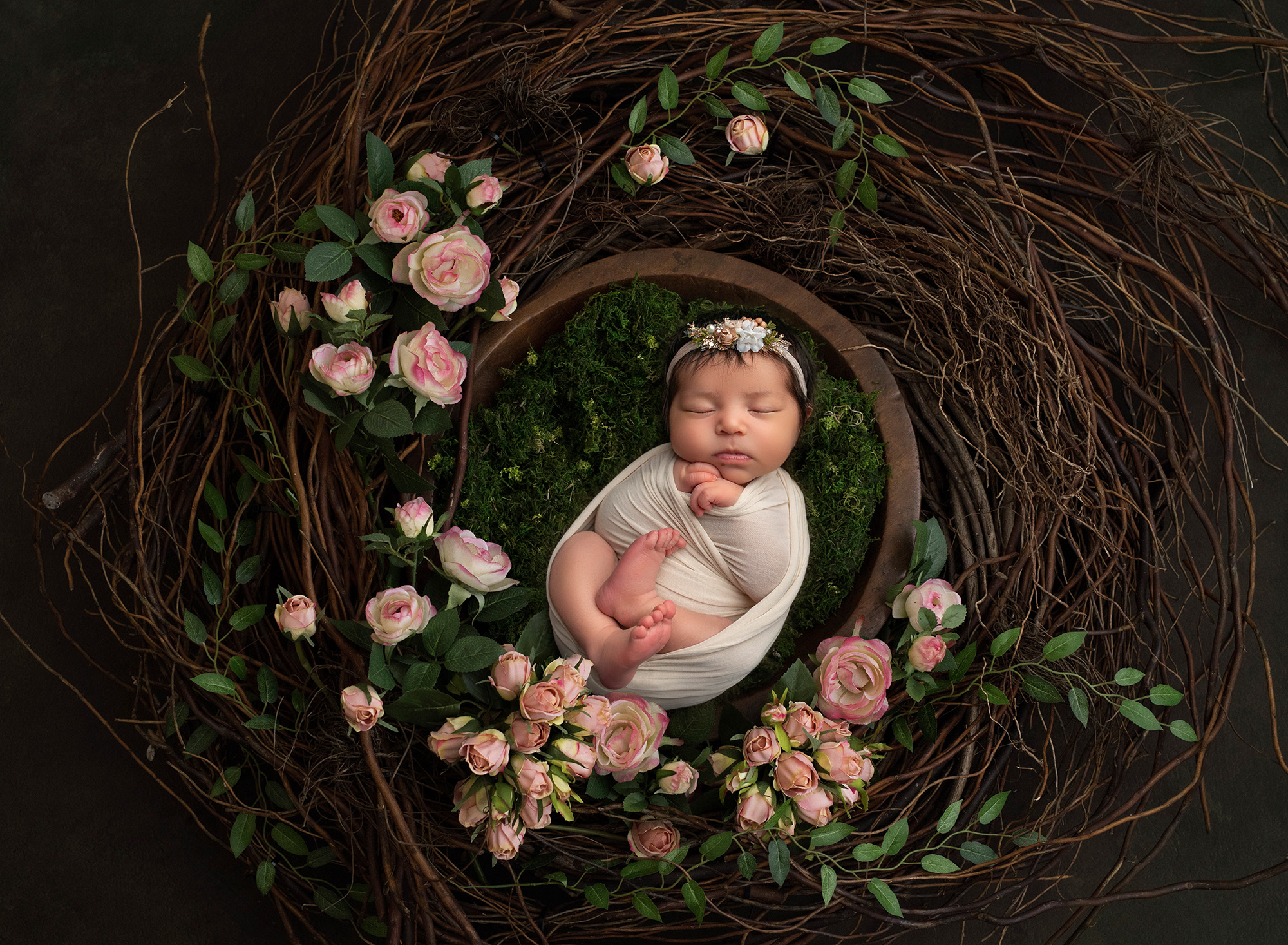 outdoorsy newborn photos newborn baby girl asleep inside wooden wreath surrounded by pink roses