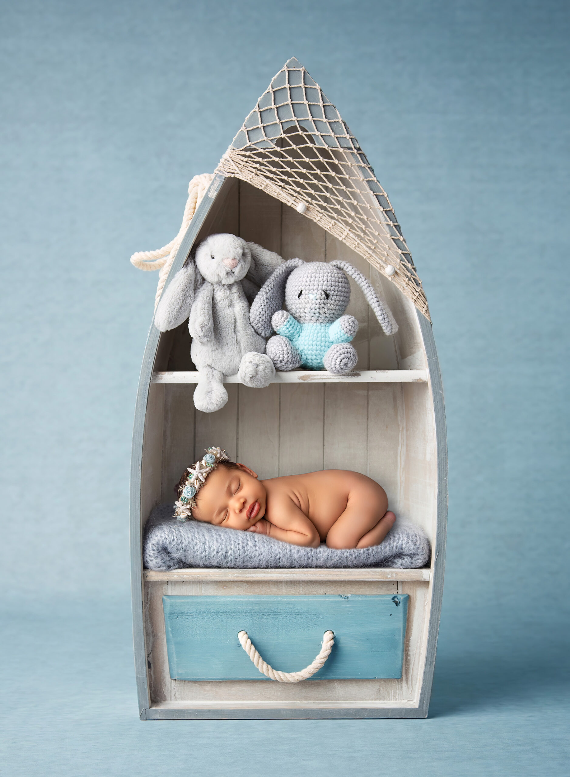 newborn photoshoot newborn baby girl asleep in a bookcase that looks like a boat